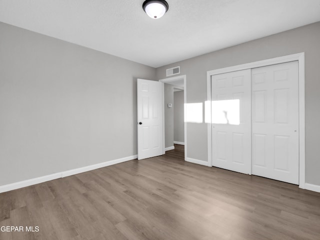 unfurnished bedroom with wood-type flooring and a closet