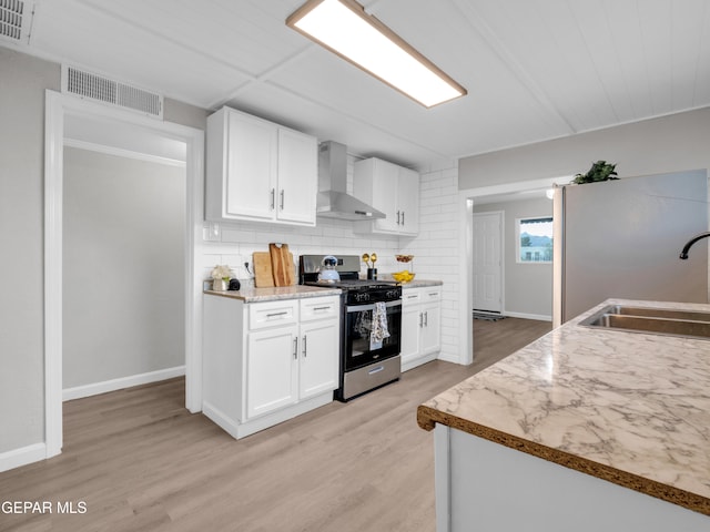 kitchen with sink, wall chimney exhaust hood, white cabinetry, stainless steel range with electric cooktop, and light hardwood / wood-style floors