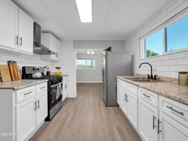 kitchen with sink, wall chimney range hood, stainless steel appliances, and plenty of natural light