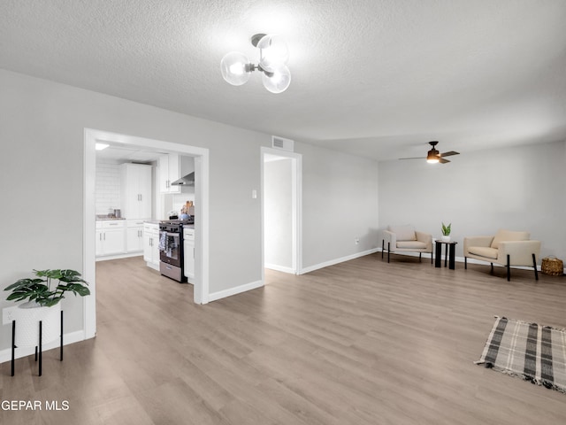 interior space with ceiling fan, a textured ceiling, and light wood-type flooring