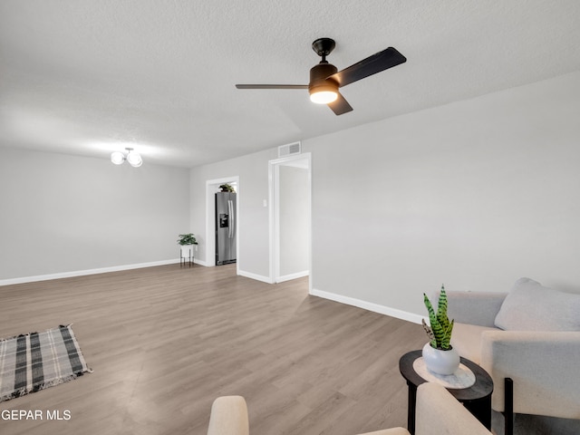 unfurnished living room with ceiling fan, hardwood / wood-style floors, and a textured ceiling