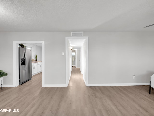 unfurnished room with a textured ceiling and light hardwood / wood-style floors