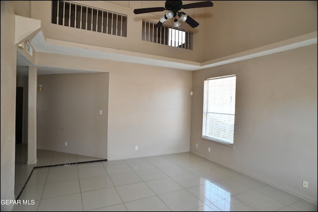 tiled spare room featuring ceiling fan and a high ceiling