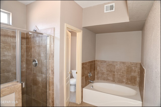 bathroom with tile patterned floors, a textured ceiling, toilet, and separate shower and tub