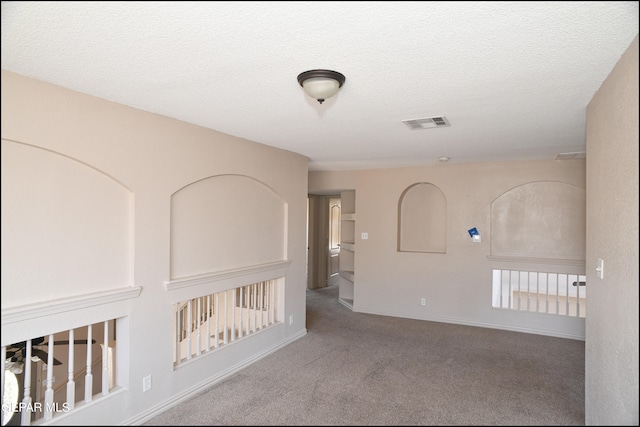 carpeted spare room featuring a textured ceiling