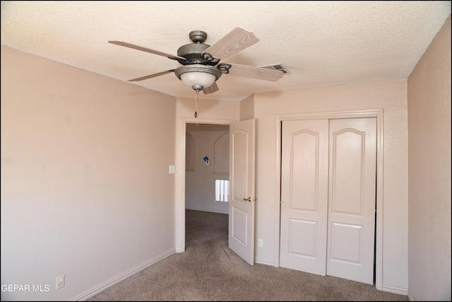 unfurnished bedroom featuring a closet, a textured ceiling, ceiling fan, and carpet floors