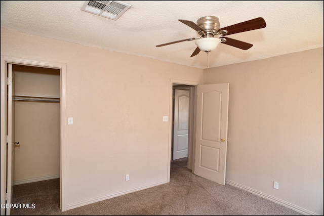 unfurnished bedroom featuring a closet, a textured ceiling, ceiling fan, and carpet floors