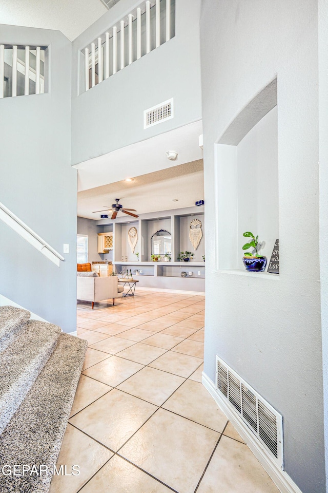 corridor featuring tile patterned flooring and a high ceiling