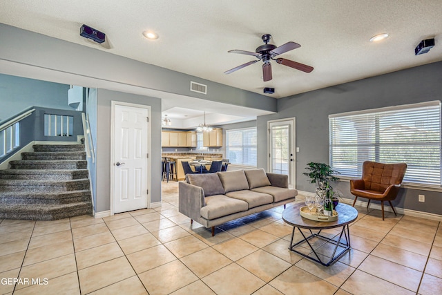 living room featuring a textured ceiling, ceiling fan with notable chandelier, a wealth of natural light, and light tile patterned flooring