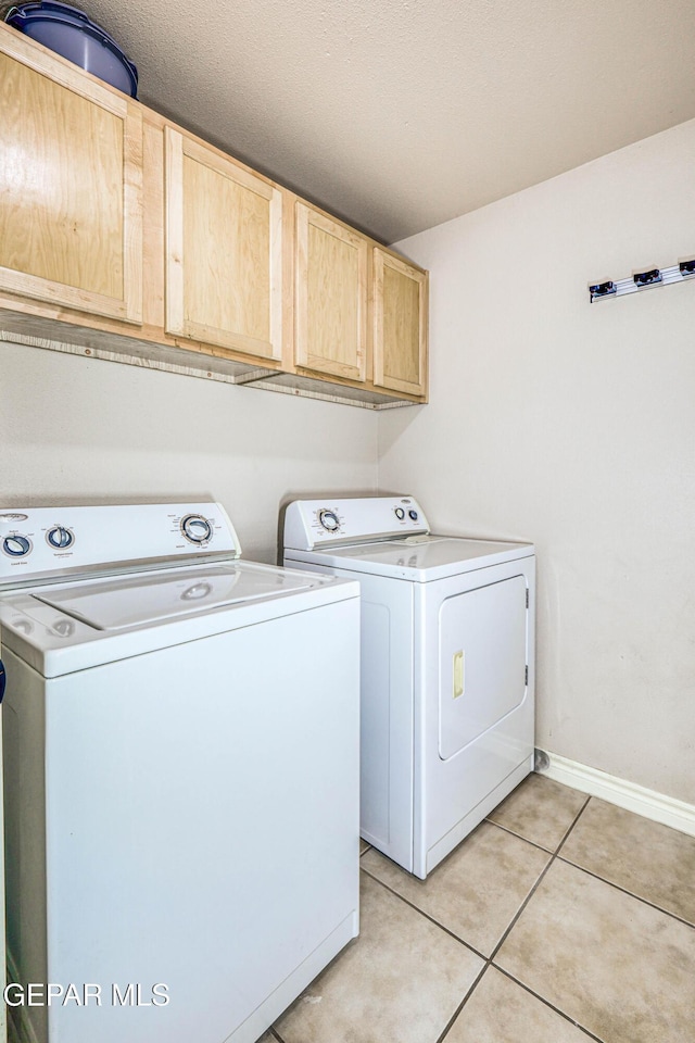 laundry area featuring cabinets, light tile patterned floors, and washing machine and clothes dryer