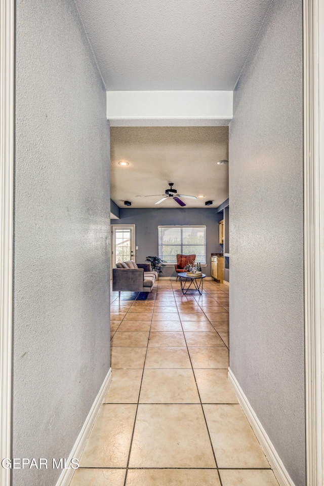 hallway with light tile patterned floors and a textured ceiling