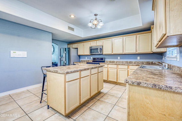 kitchen featuring a tray ceiling, a kitchen island, and appliances with stainless steel finishes