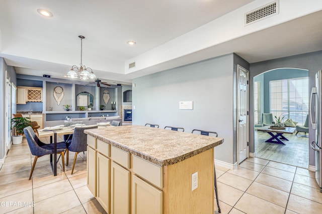 kitchen featuring ceiling fan with notable chandelier, a center island, light tile patterned flooring, and decorative light fixtures