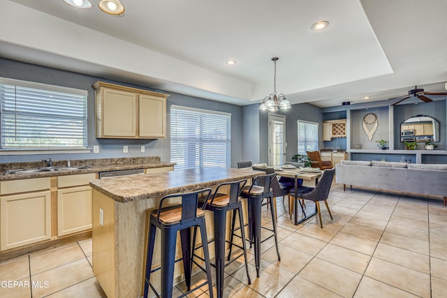 kitchen featuring a center island, sink, hanging light fixtures, light tile patterned floors, and ceiling fan with notable chandelier