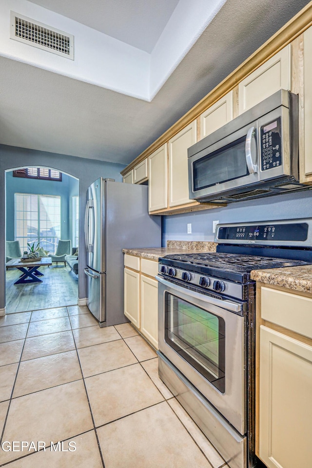 kitchen with light tile patterned floors, stainless steel appliances, and cream cabinets