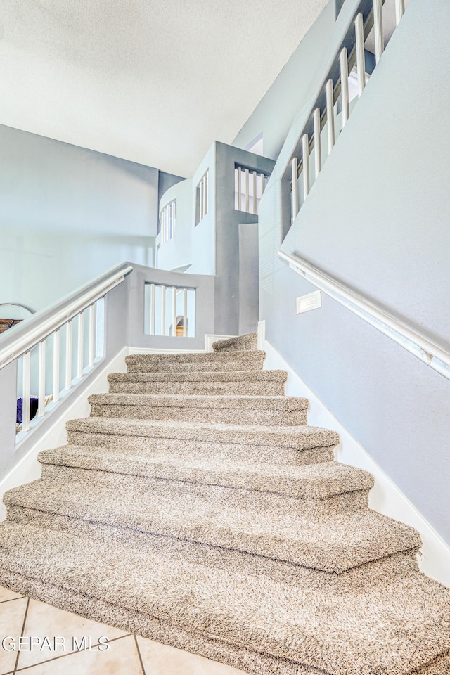 stairway with tile patterned floors and a textured ceiling