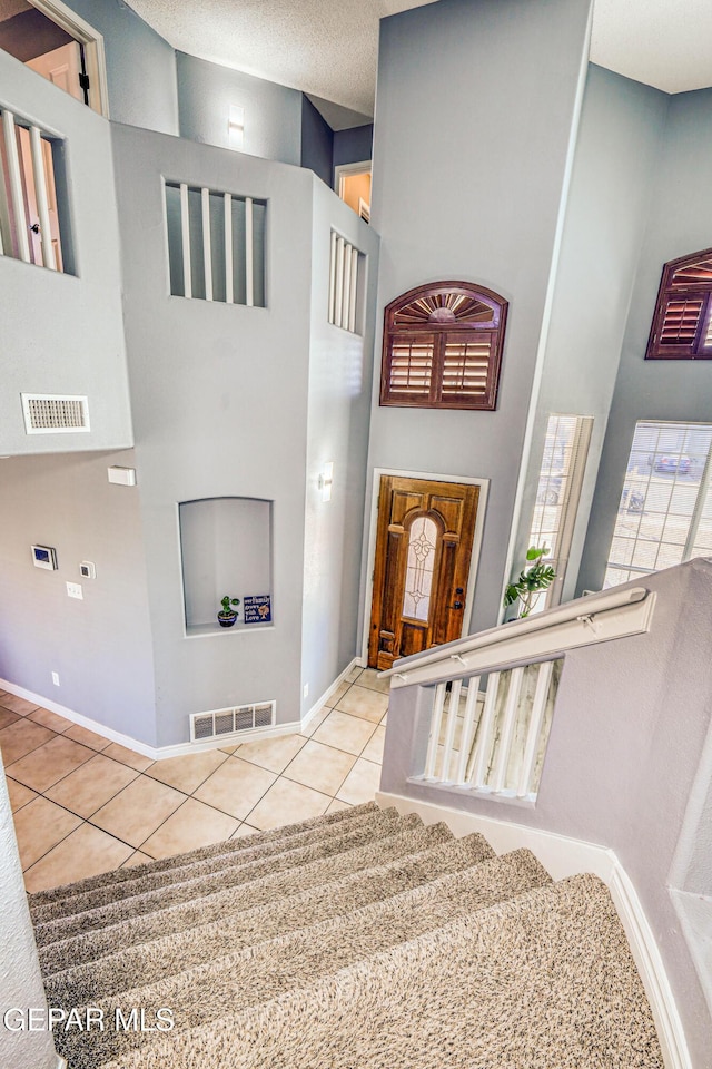 staircase featuring tile patterned flooring and a towering ceiling