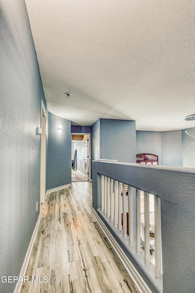 hallway with hardwood / wood-style floors and a textured ceiling