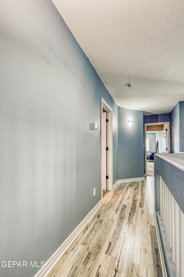 corridor featuring light hardwood / wood-style floors and a textured ceiling