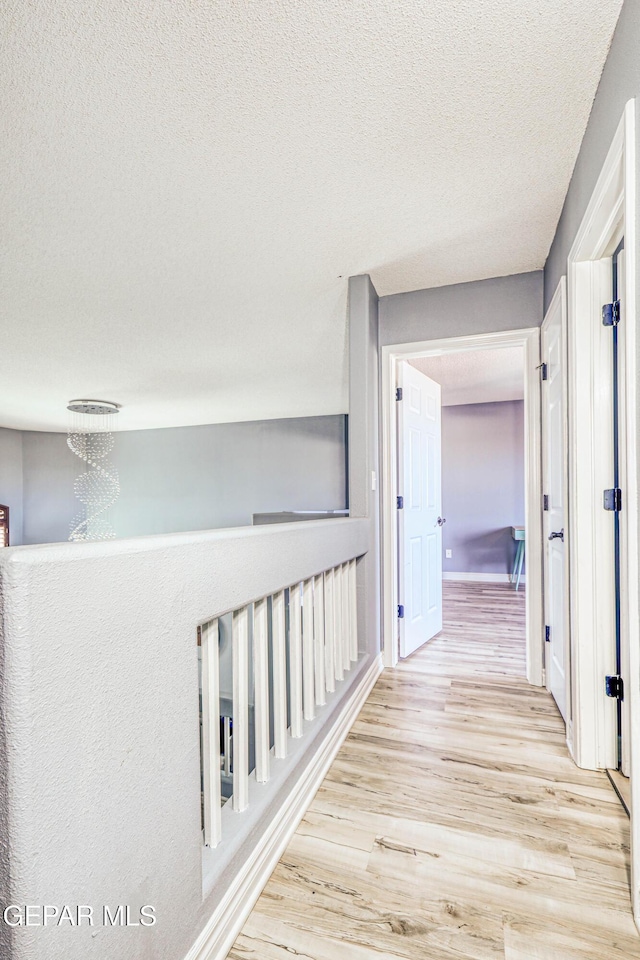 hall featuring light hardwood / wood-style floors and a textured ceiling