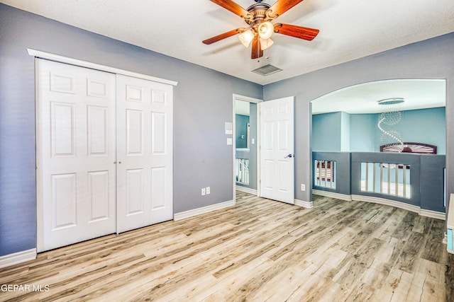 unfurnished bedroom with ceiling fan, light wood-type flooring, a textured ceiling, and a closet