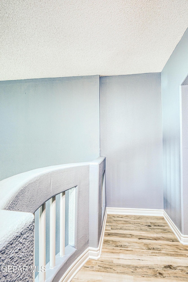 hall featuring wood-type flooring and a textured ceiling