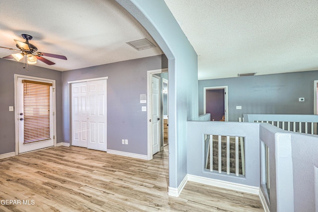 interior space featuring ceiling fan, light hardwood / wood-style flooring, and a textured ceiling