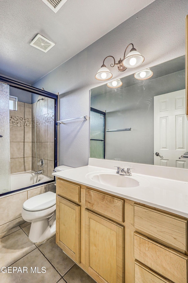 full bathroom featuring tile patterned flooring, bath / shower combo with glass door, a textured ceiling, toilet, and vanity