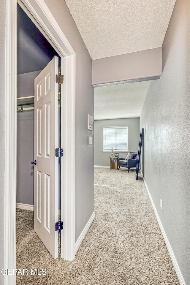 corridor featuring carpet flooring and a textured ceiling