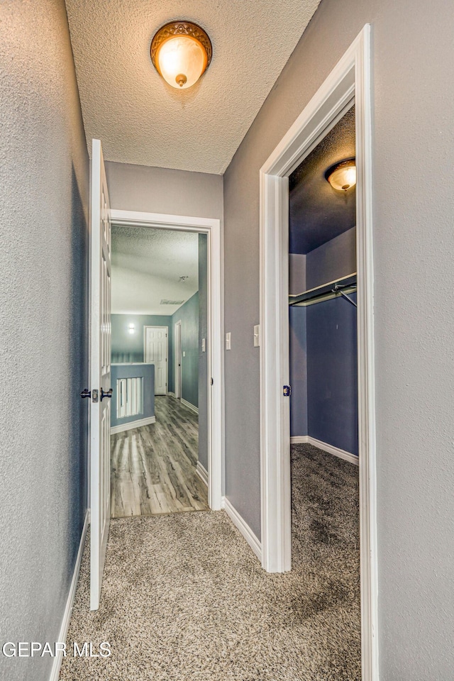 hallway featuring carpet flooring and a textured ceiling