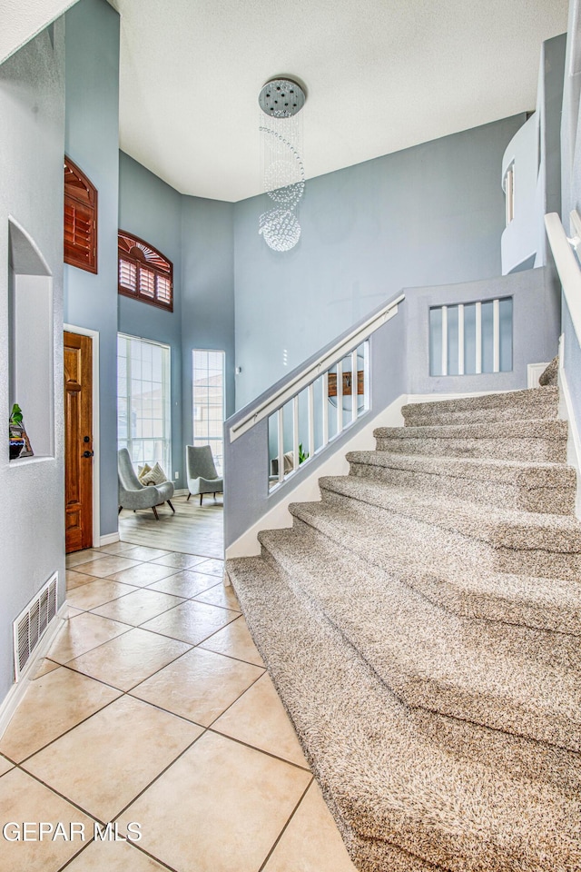 staircase featuring tile patterned floors and a towering ceiling