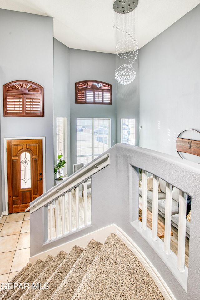 staircase featuring tile patterned flooring, a high ceiling, and an inviting chandelier