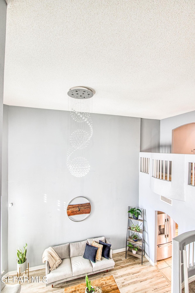 living room featuring light hardwood / wood-style flooring, a textured ceiling, and an inviting chandelier