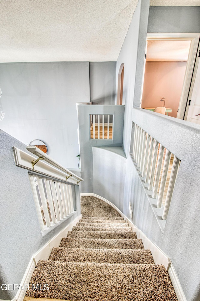 staircase with carpet and a textured ceiling