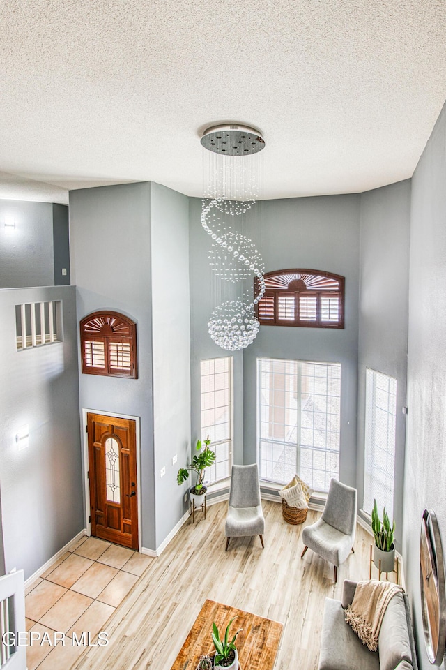 interior space with a high ceiling, a chandelier, a textured ceiling, and light hardwood / wood-style floors