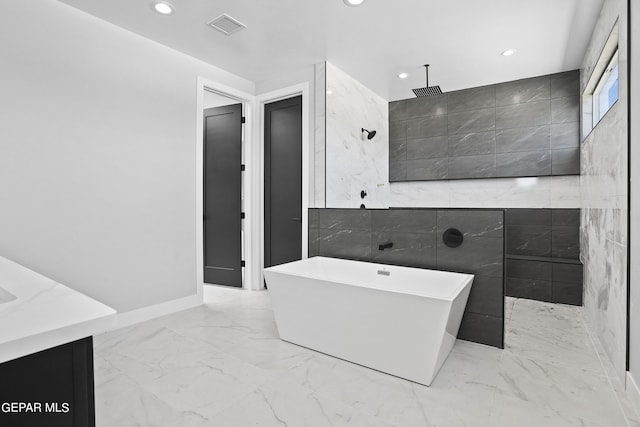 bathroom featuring vanity, plus walk in shower, and tile walls