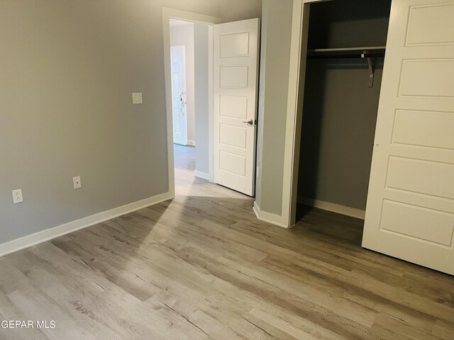 unfurnished bedroom featuring light hardwood / wood-style flooring and a closet