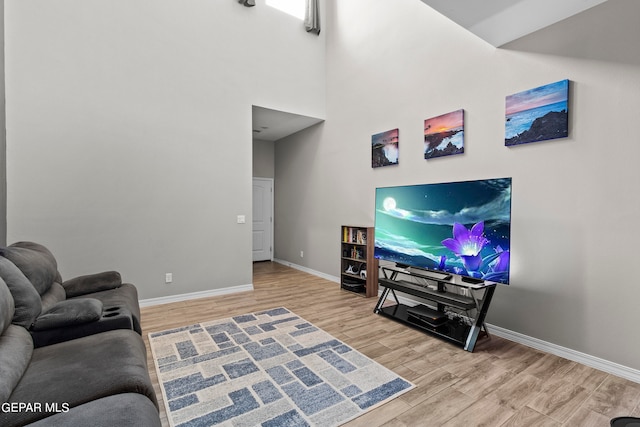 living room with a towering ceiling and light hardwood / wood-style flooring