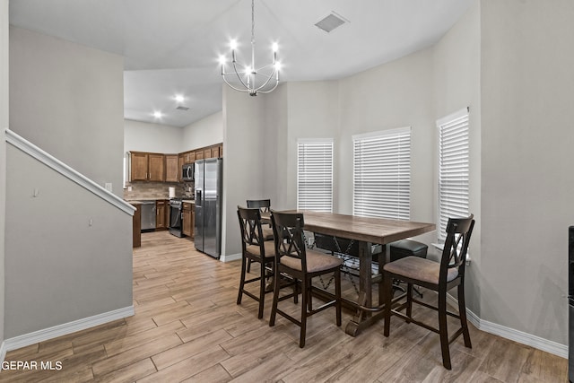 dining space with light hardwood / wood-style flooring and a chandelier