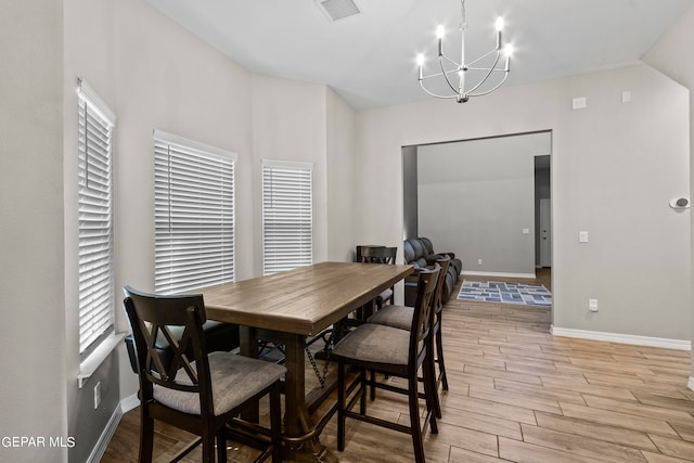 dining area featuring an inviting chandelier, vaulted ceiling, and light hardwood / wood-style floors