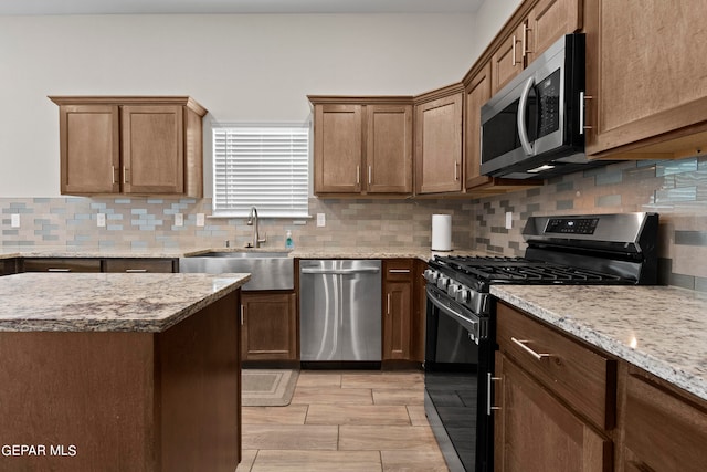 kitchen with tasteful backsplash, light stone countertops, sink, light wood-type flooring, and stainless steel appliances