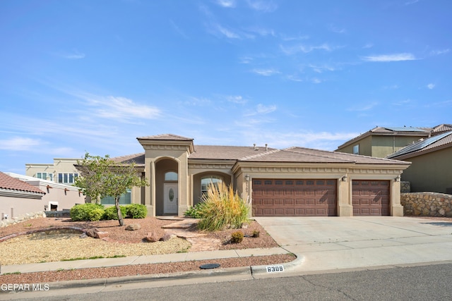 view of front facade featuring a garage, driveway, a tiled roof, and stucco siding