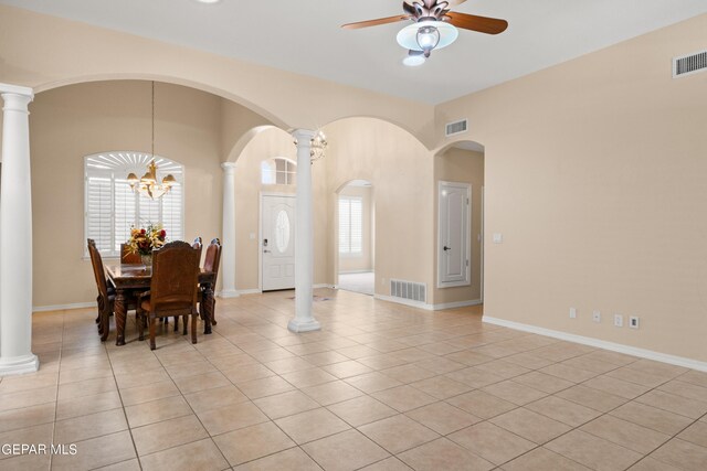 dining space featuring decorative columns, ceiling fan with notable chandelier, and light tile patterned floors