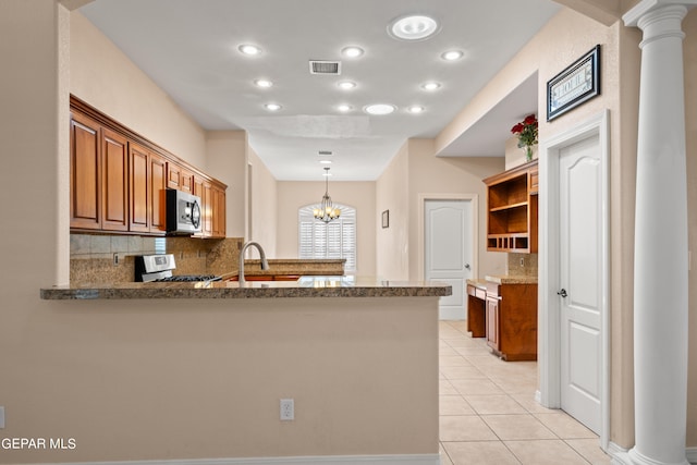 kitchen featuring stove, tasteful backsplash, kitchen peninsula, light tile patterned floors, and ornate columns