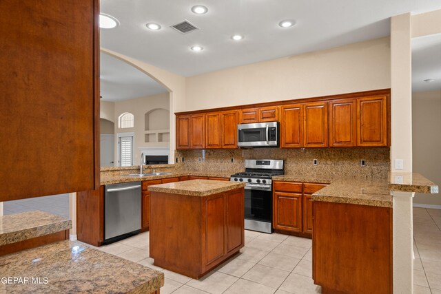 kitchen with light tile patterned flooring, stainless steel appliances, decorative backsplash, sink, and kitchen peninsula