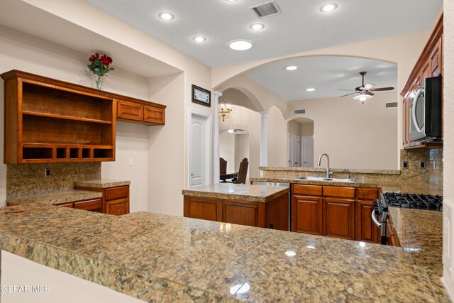 kitchen featuring stainless steel appliances, sink, kitchen peninsula, decorative backsplash, and ceiling fan