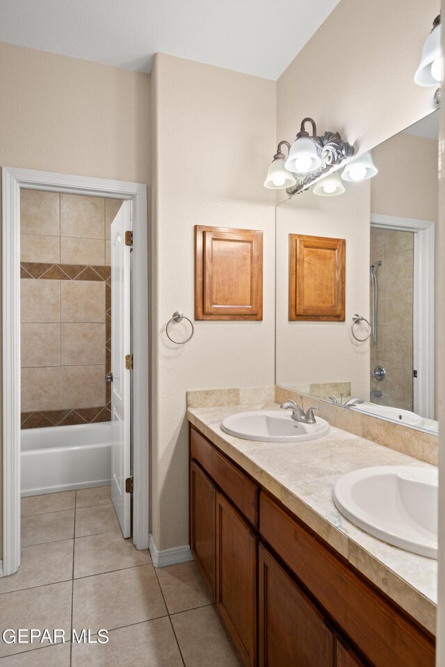 bathroom with tile patterned floors, double sink vanity, and tiled shower / bath