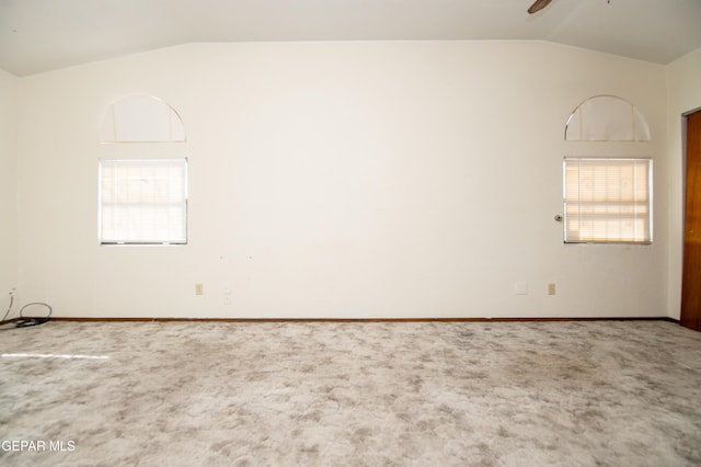 empty room with ceiling fan, vaulted ceiling, and carpet floors