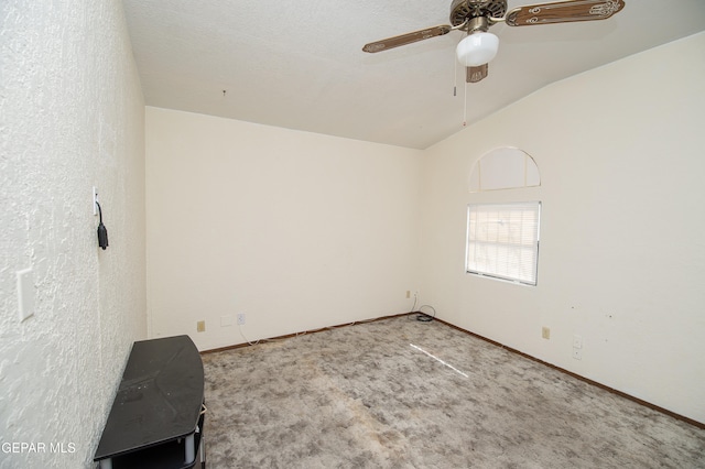 carpeted spare room featuring a textured ceiling, ceiling fan, and vaulted ceiling