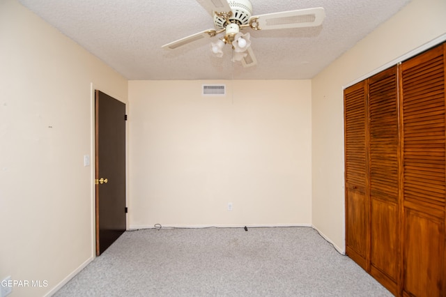 bedroom featuring a closet, a textured ceiling, light colored carpet, and ceiling fan